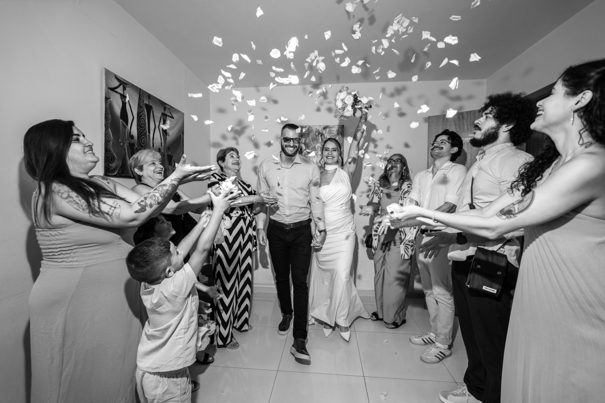 Foto do casal passando pelo corredor de pétalas, onde o fotógrafo dirigiu e conduziu a cena improvisada no próprio catório de notas.