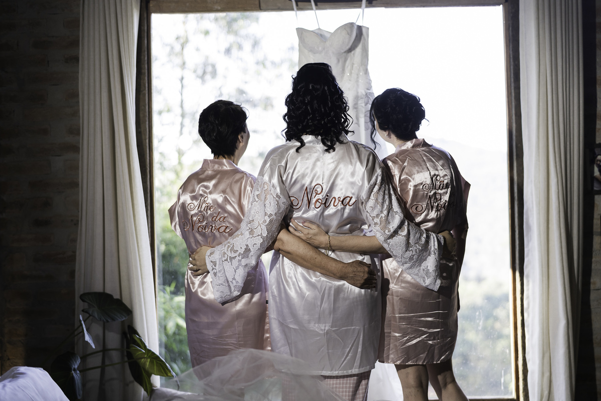 Foto tradicional da noiva com a mãe e a sogra, todas vestindo o hoby personalizado.