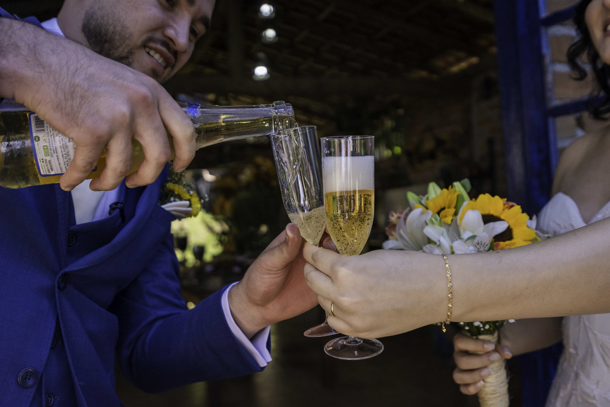 Foto documental que registrou o noivo servindo espumante para sua esposa, e em seguida um brinde clásiico de casamento.
