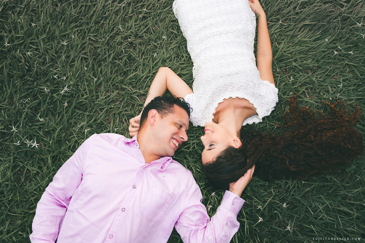 noivos fazendo carinho deitados no gramado e sorrindo olhando um para o outro