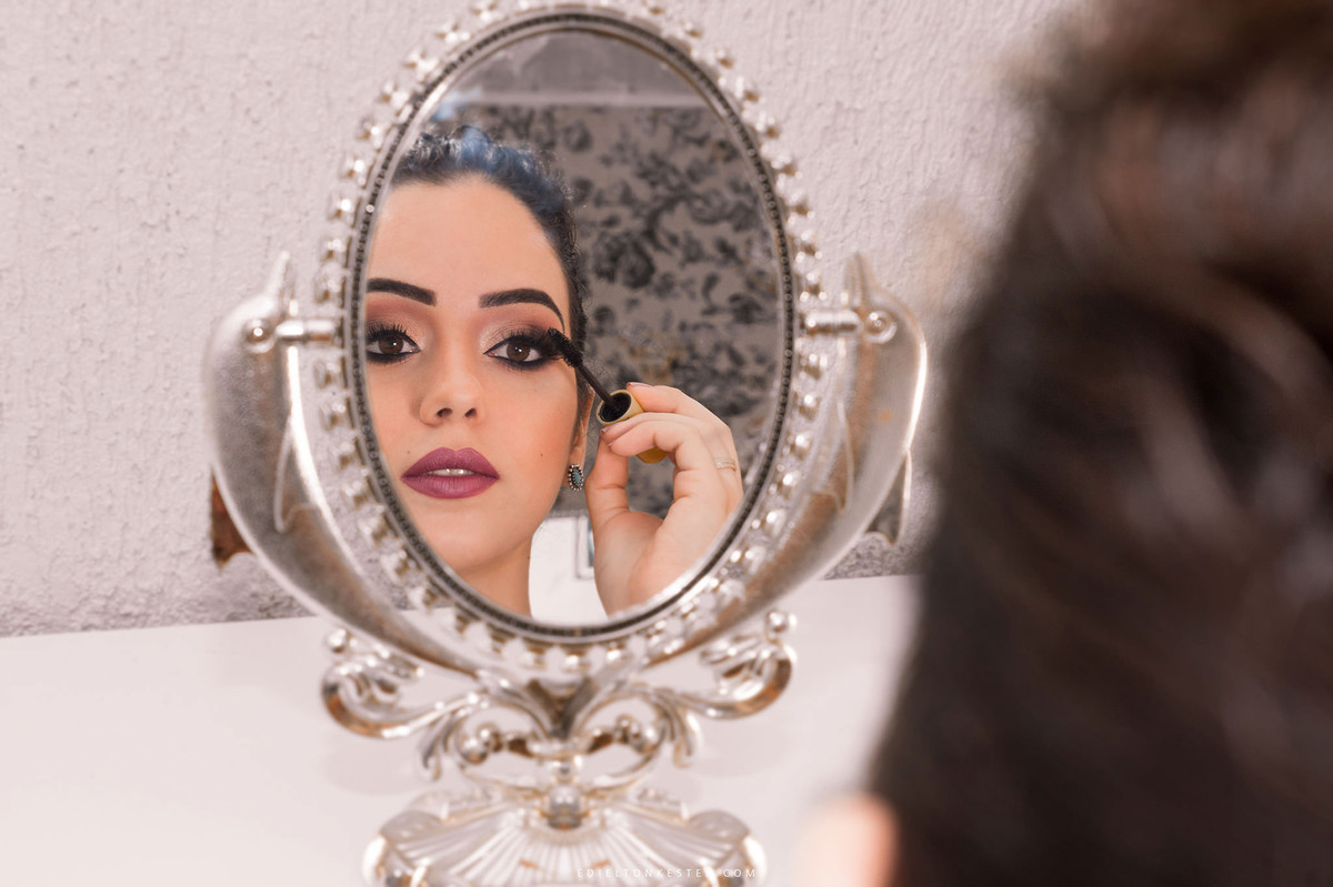noiva se maquiando olhando para foto em seu making of para o casamento, fotos feitas pelo fotografo de casamento edielton kester
