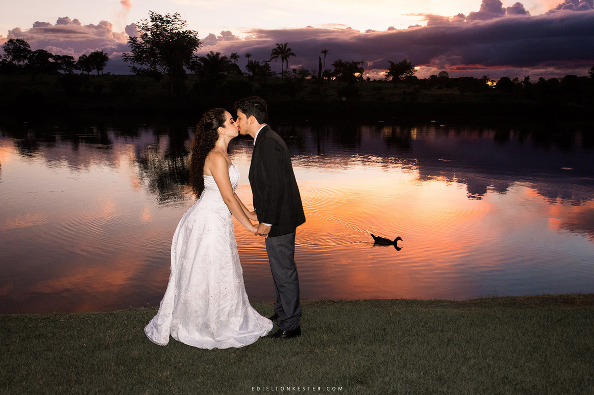 noivos se beijando no por do sol e pato nadando no lago ao redor