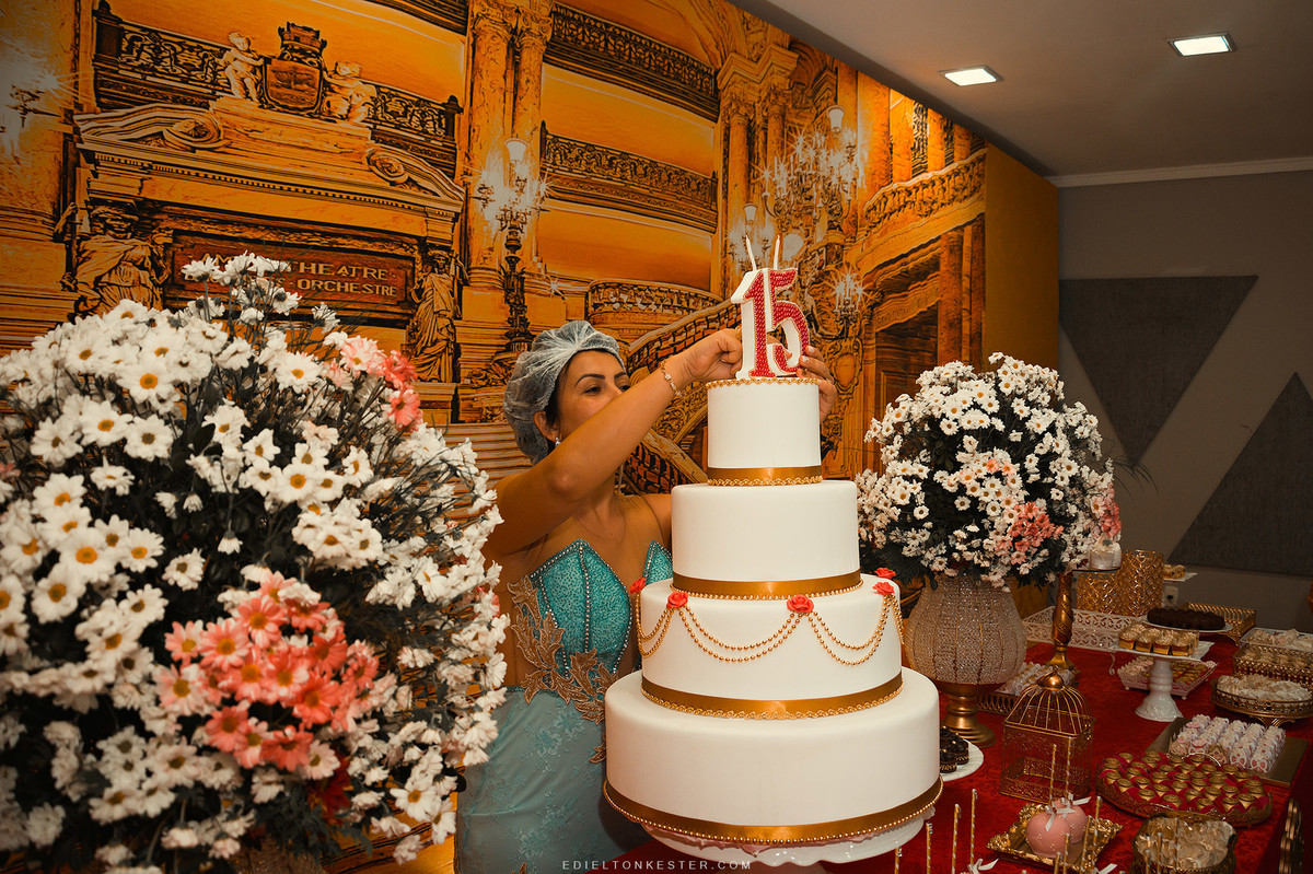 mae da aniversariante colocando a vela de 15 anos no bolo