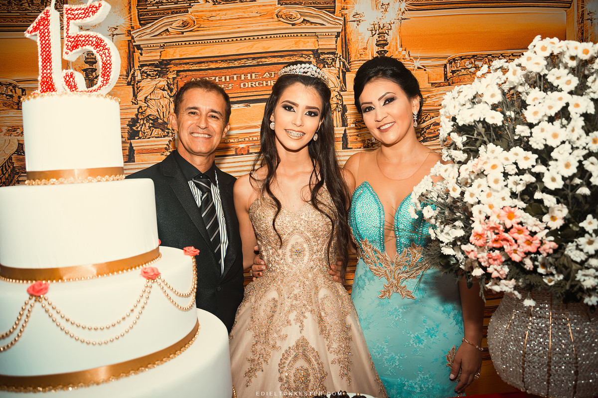 debutante com seus pais em foto perto do bolo