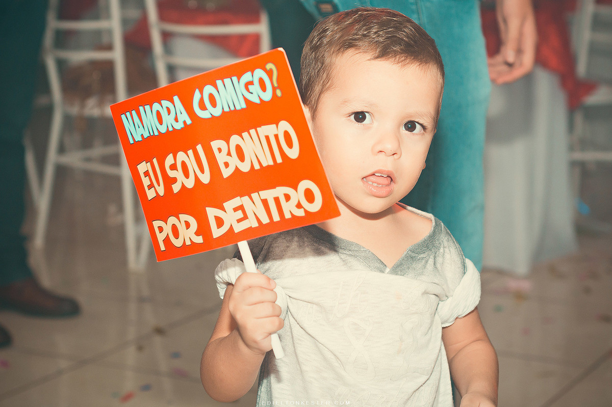 garotinho segurando plaquinha engraçada