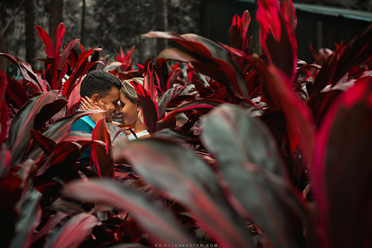casal se olhando e sorrindo em meio a flores em ensaio pre casamento