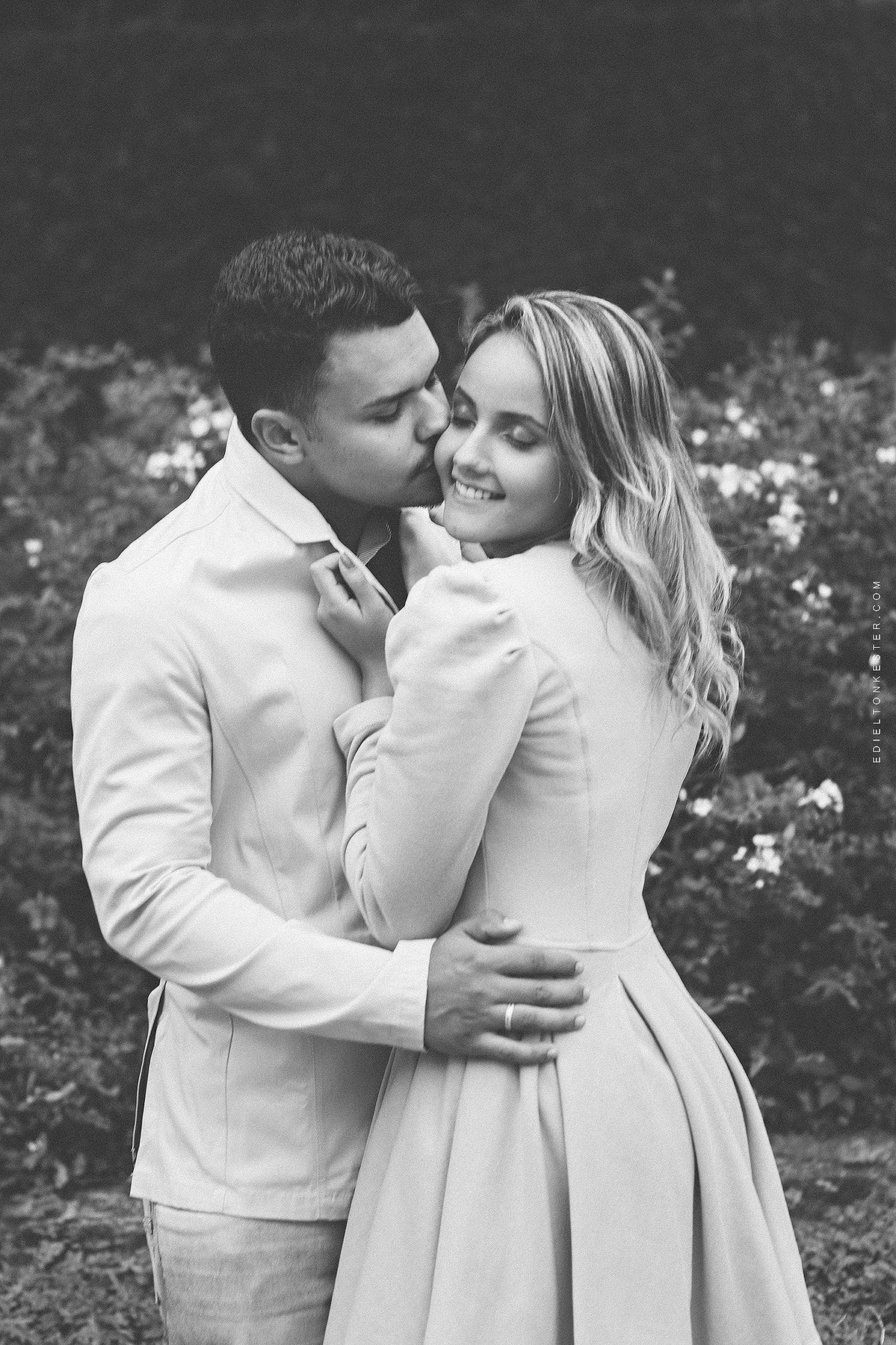 noivos abraçados e noivo beijando o rosto de sua noiva