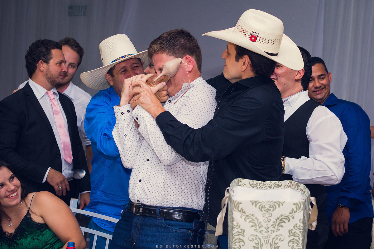 foto do corte da gravata com convidado cheirando o sapato da noiva