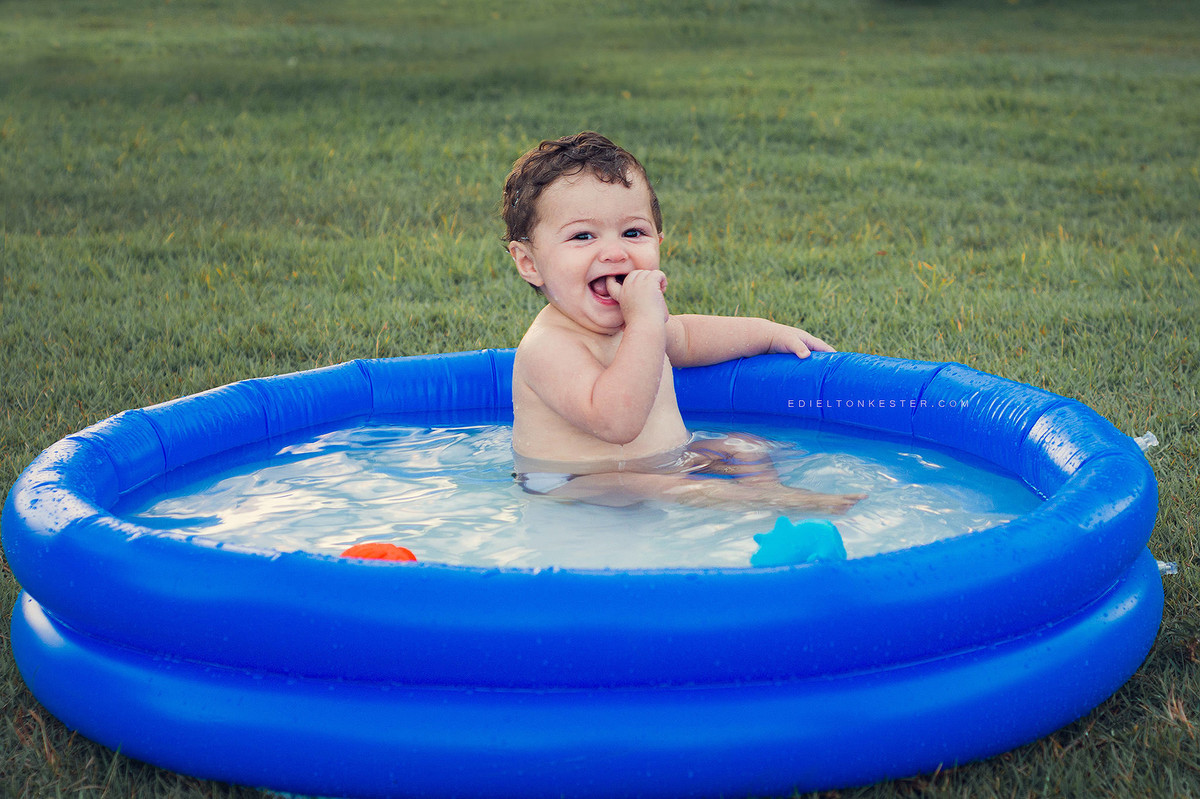 criança tomando banho e se divertindo sorrindo na piscina com patinho