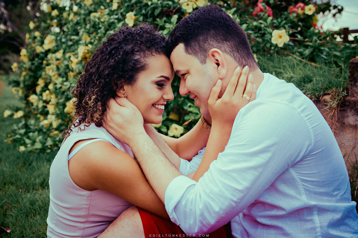 casal sentado em meio a flores e sorrindo em ensaio pre casamento pelo fotografo edielton kester em fotografo rondonia