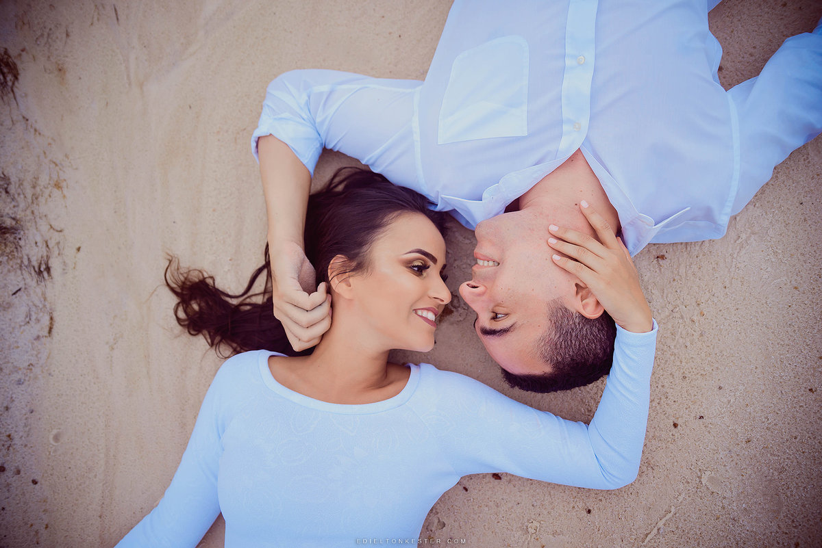 casal se olhando deitados na areia