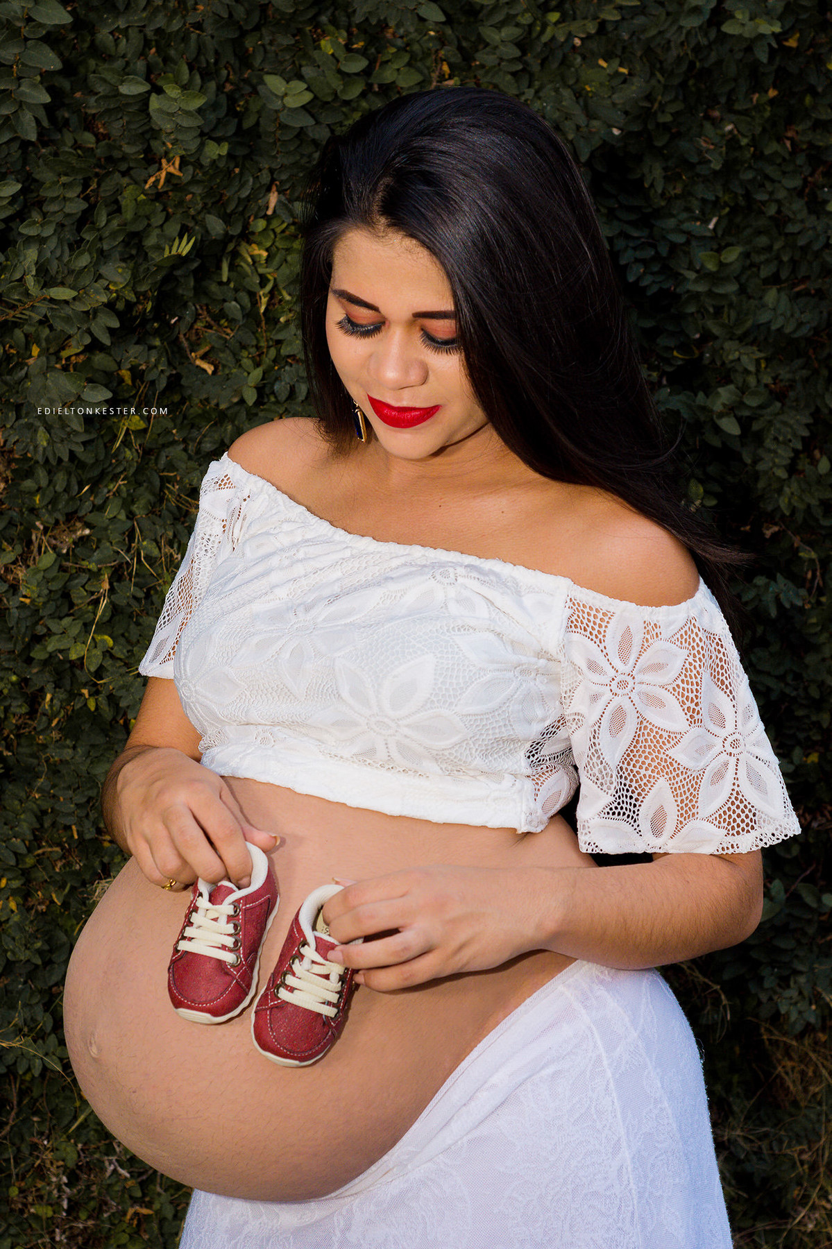 gestante segurando sapatinho do filho na barriga em ensaio de gravidez