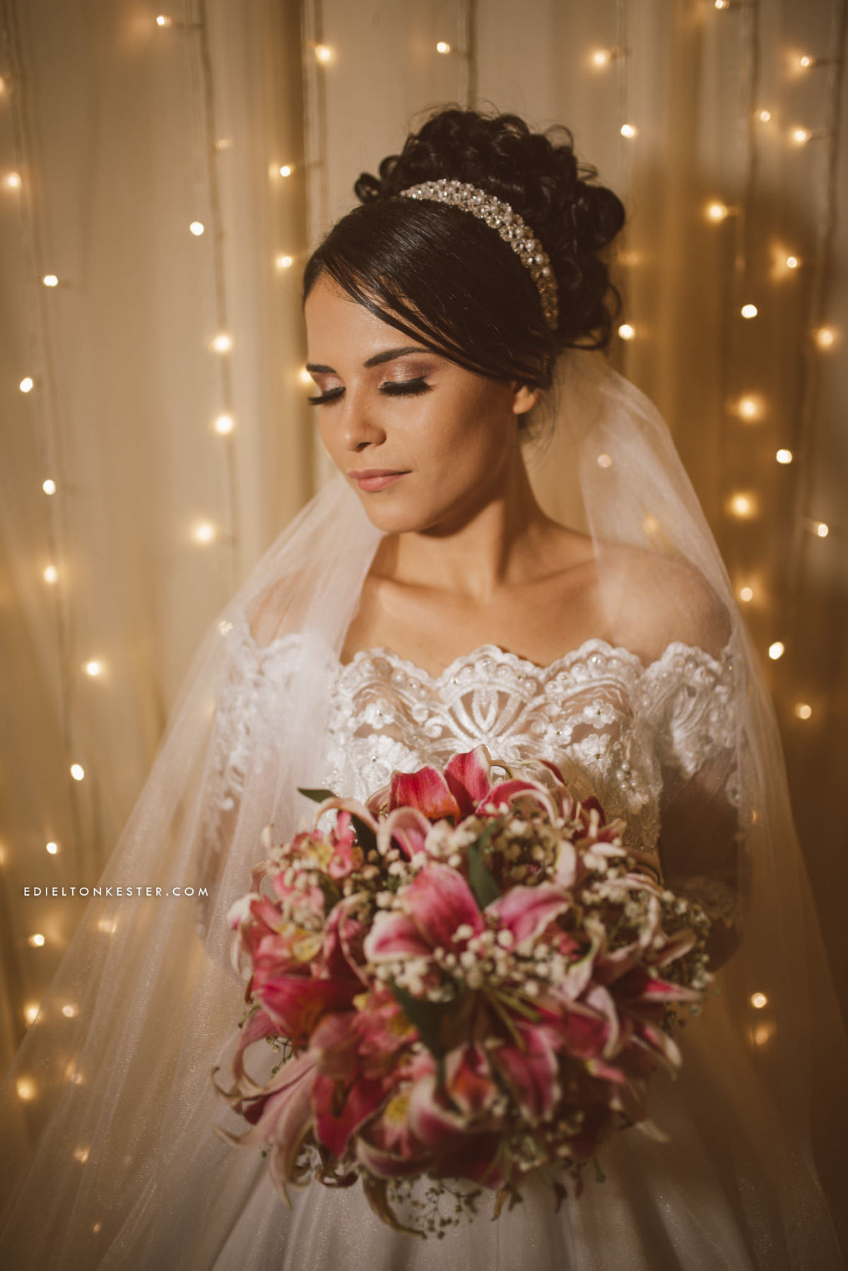 noiva olhando para seu buque enquanto posa para fotos em seu casamento em frente a luzes de natal em ji paraná