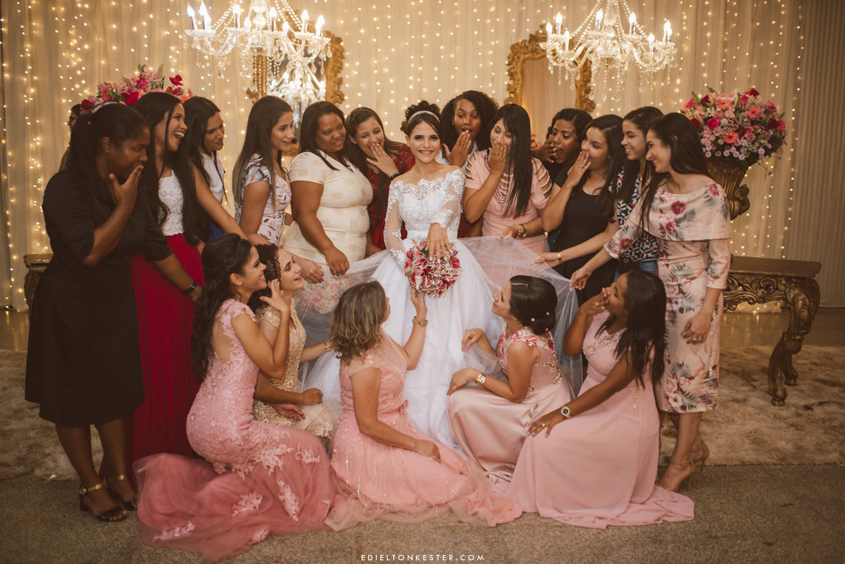 noiva dando risada em foto com suas amigas e mostrando a aliança