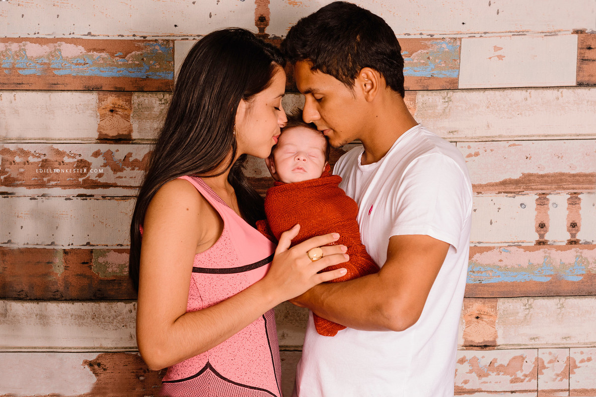 pais beijando o filho em ensaio newborn