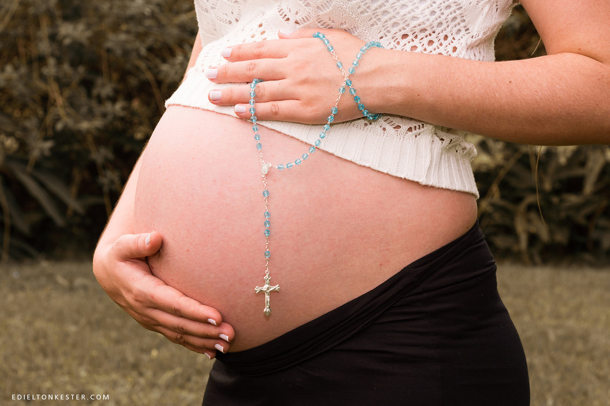gravida com terço na barriga em momento de fé
