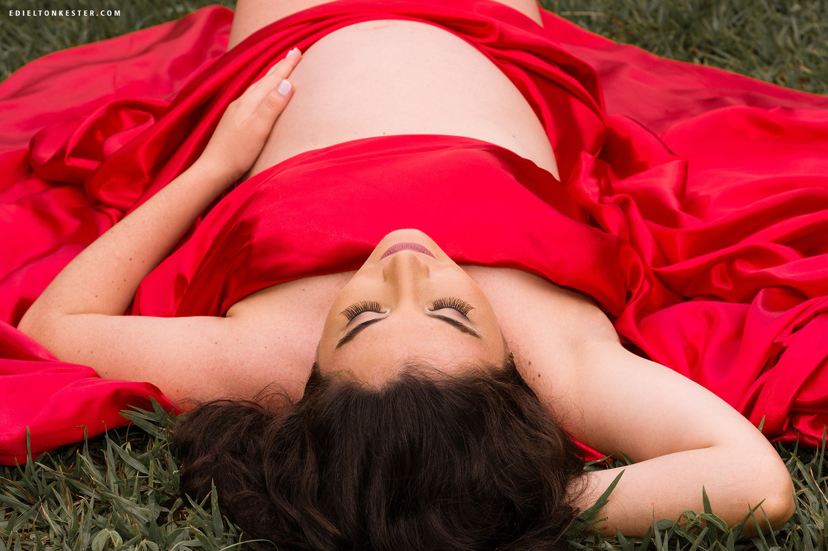 gravida em momento de ternura deitada e com tecido vermelho