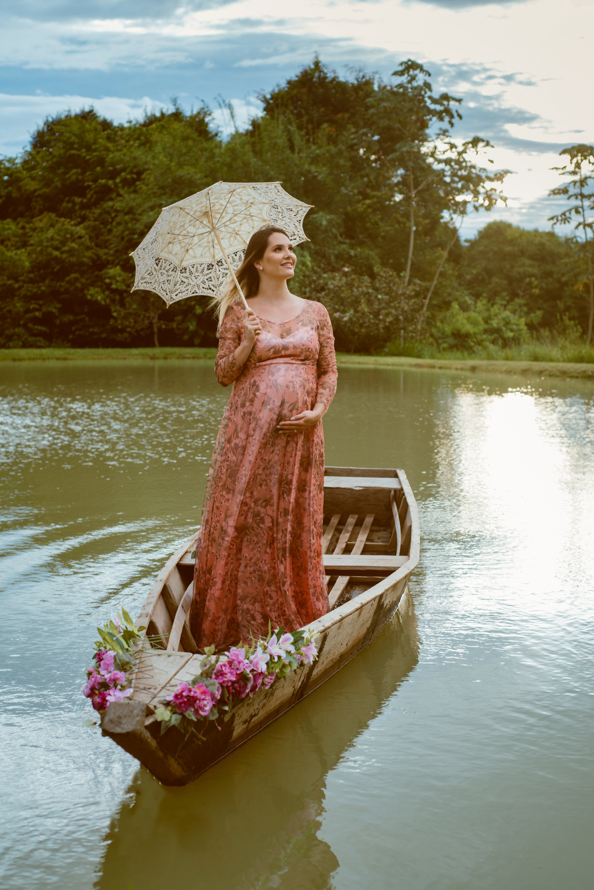 gestante segurando guarda chuva de renda dentro de um barco