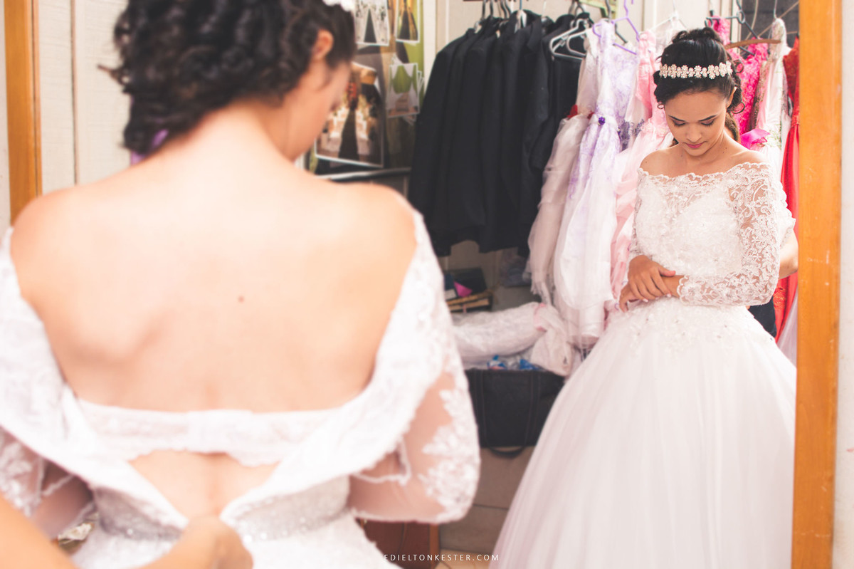 noiva com a cabeça abaixada enquanto coloca o vestido, abotoando vestido de noiva