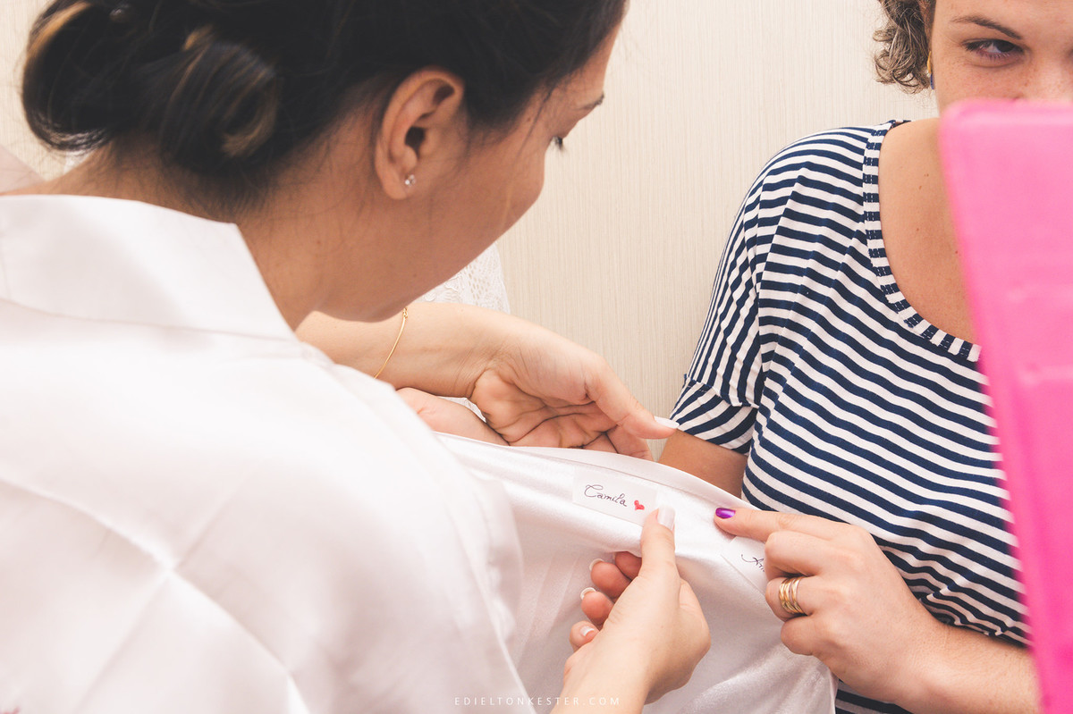 noiva escrevendo nomes na barra do vestido de noiva