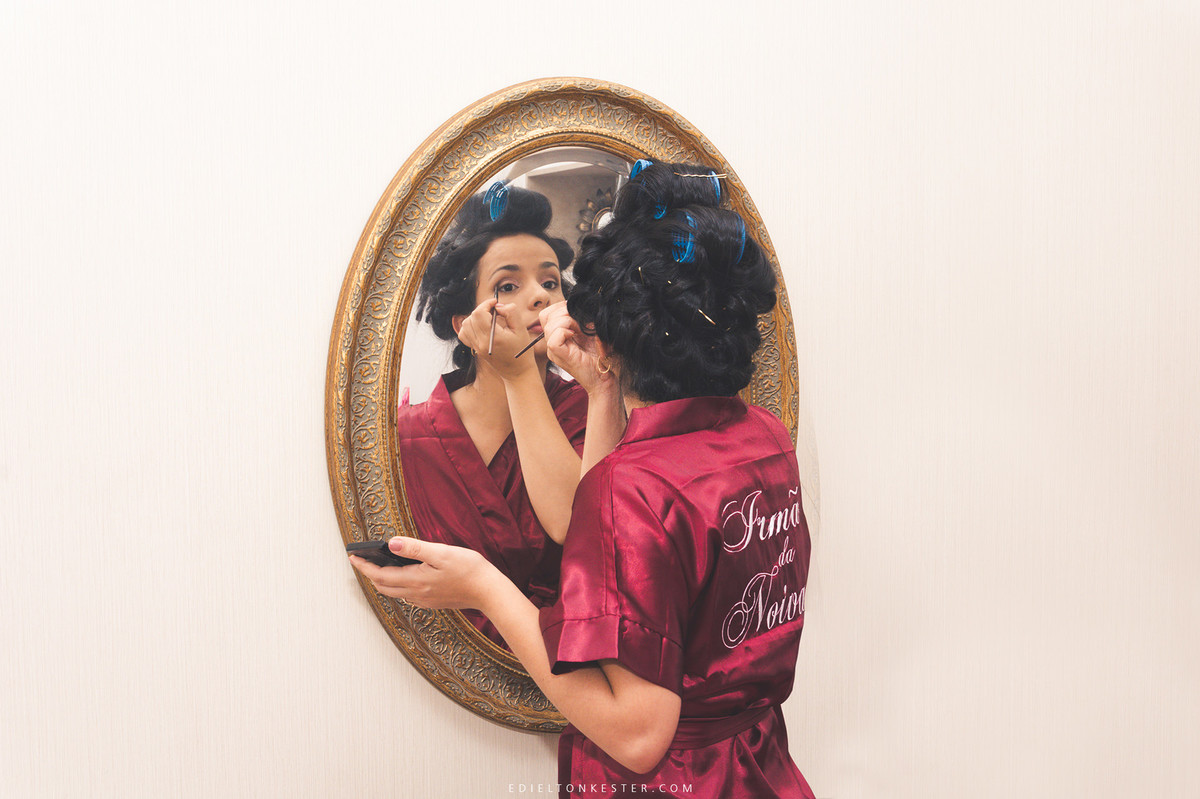 irma da noiva se maquiando em frente ao espelho