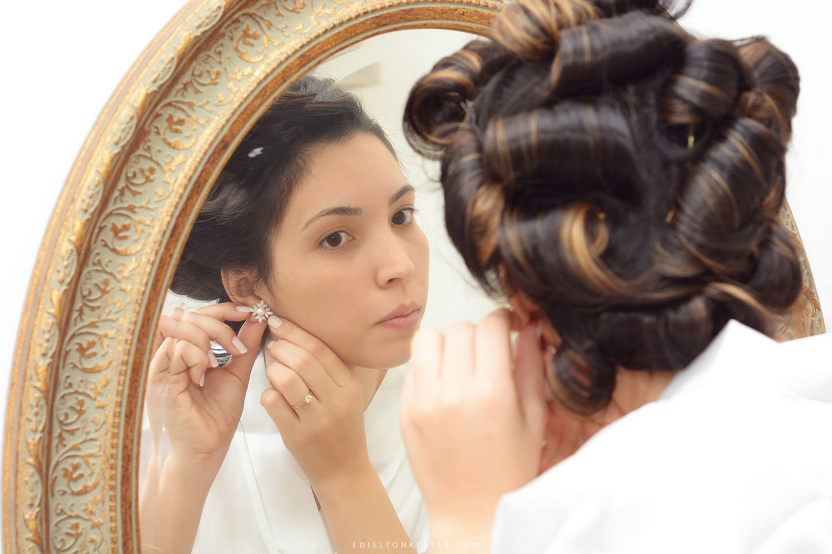 noiva colocando brinco em frente ao espelho em seu making of
