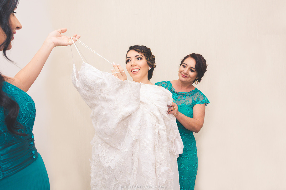 noiva com sua mae e irma ajudando a vestir o lindo vestido de noiva