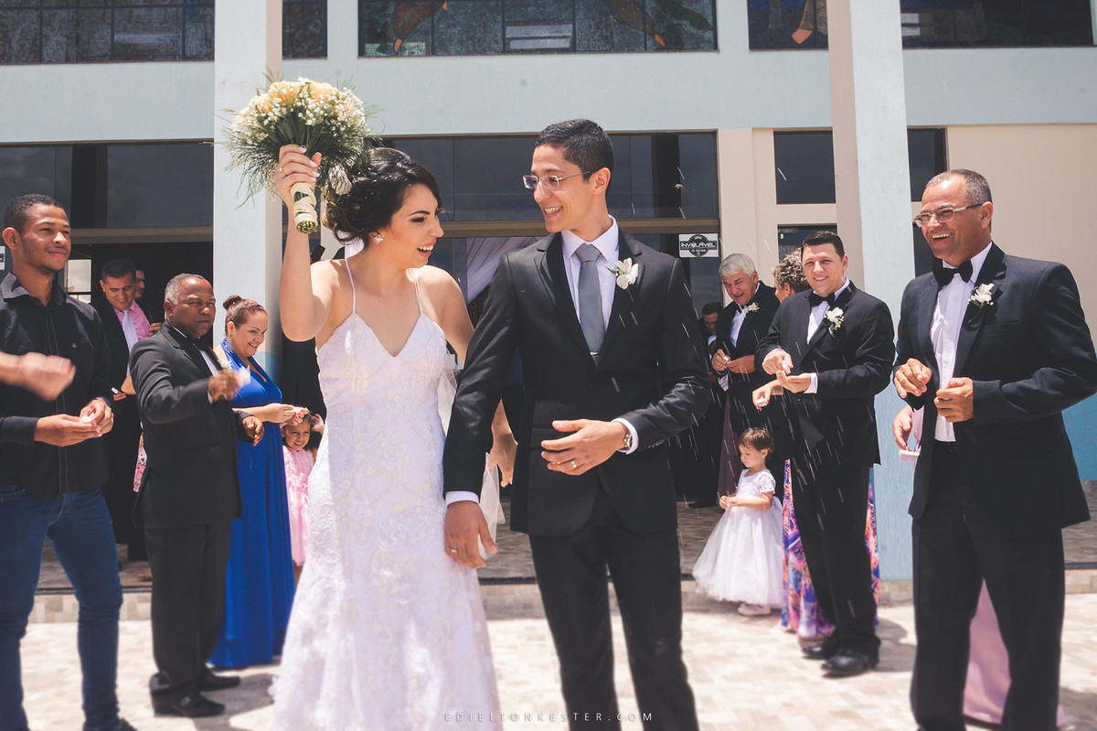 noivos se olhando e sorrindo com chuva de arroz na frente da igreja