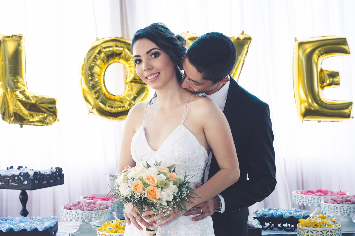 noivos posando para fotos na mesa do bolo com fotos pelo edielton kester