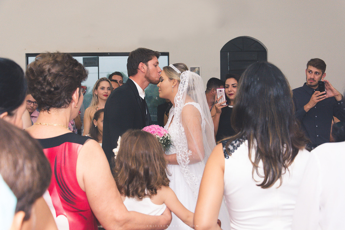 noivo beijando testa da noiva na entrada do casamento