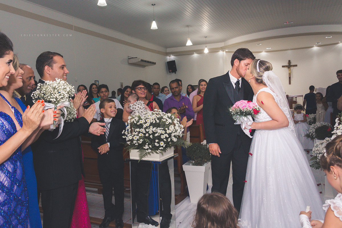 beijo do casal no casamento com convidados aplaudindo