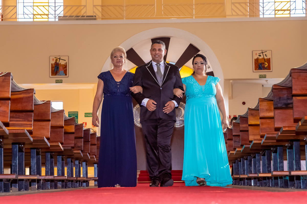 O noivo sendo Conduzido pelo corredor pela Mamãe e a Irmã