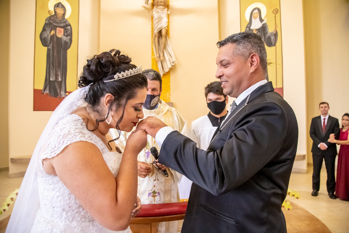 após colocar a aliança no dedo do noivo, a noiva beija a mão dele