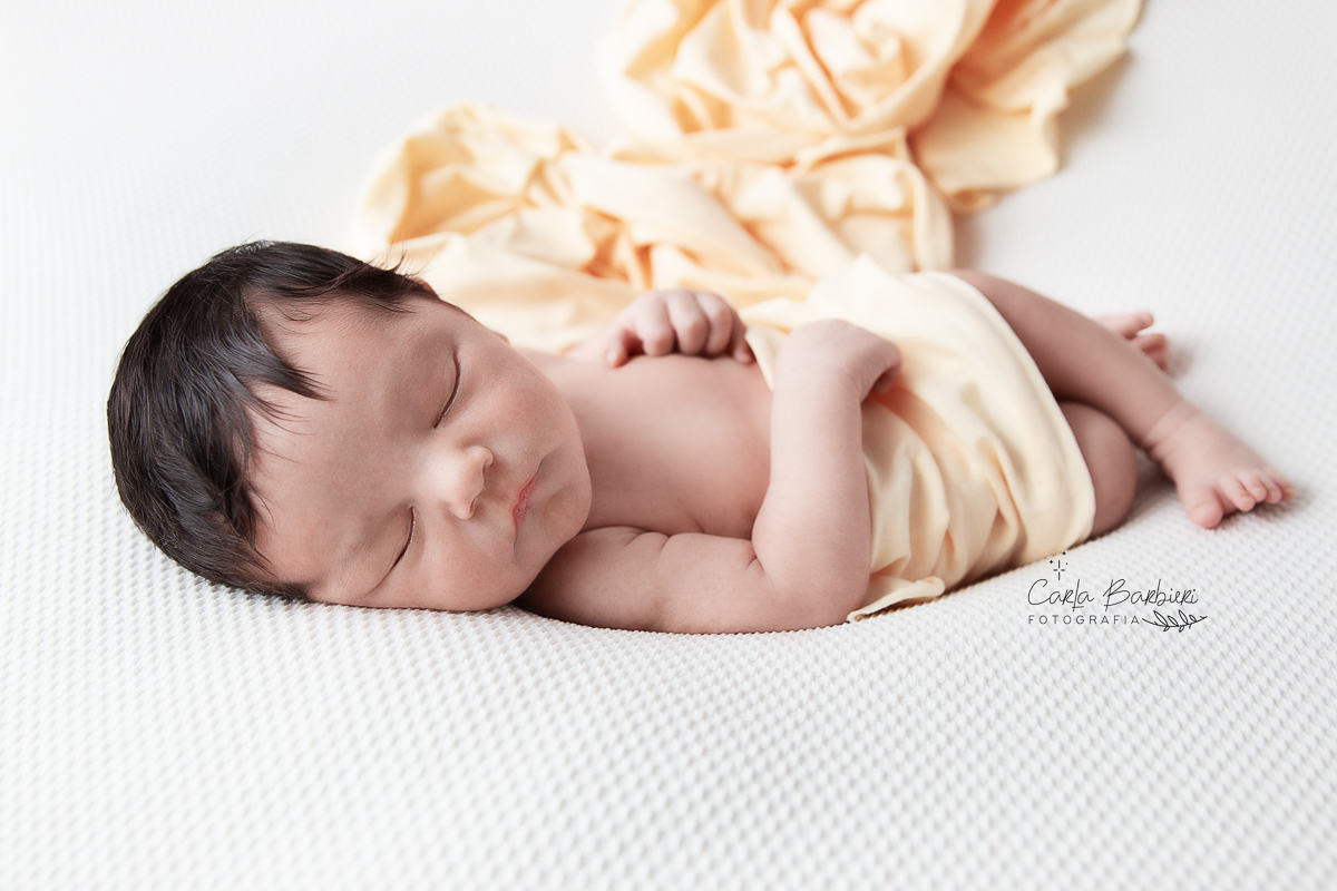 Bebê Samuel em fotografia de barriga para cima coberto com wrap amarelo