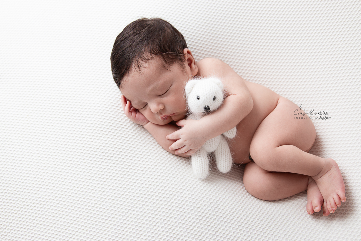 foto do recé-nascido Samuel na pose de ladinho segurando um ursinho