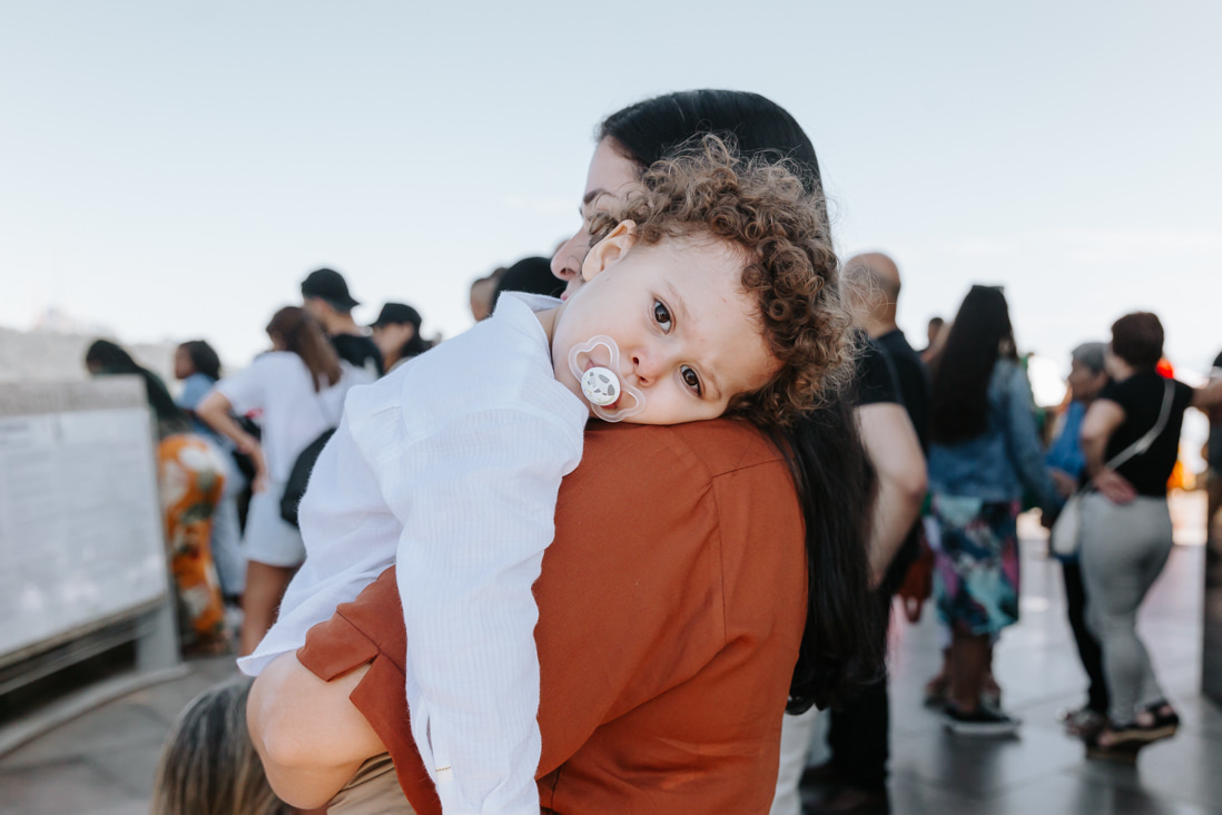 menino de  3 anos no colo da mae aguarda seu batizado no cristo redentor