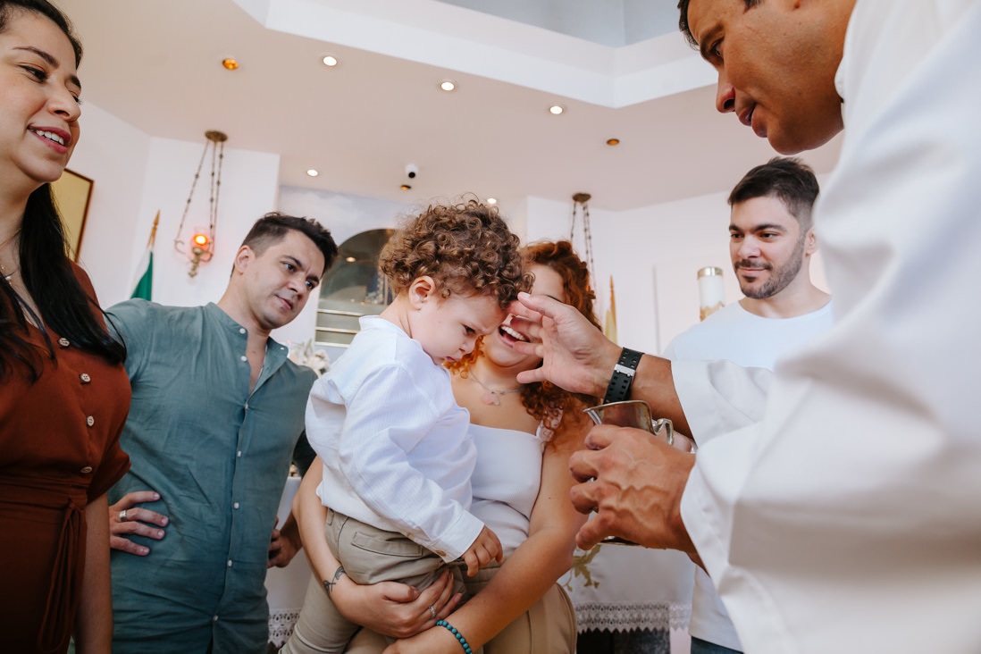 padre molha testa da criança na pia batismal do cristo