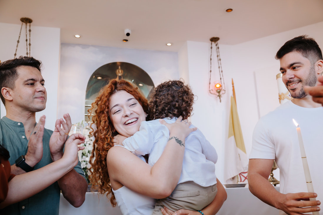 criança abraça madrinha apos ritual de batismo