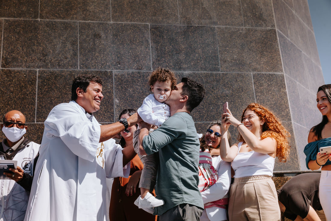 padre entrega filho aos pais em batismo no cristo redentor