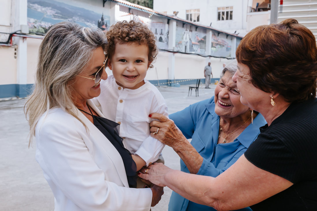 bisavo, avo e tia brincam com neto de 3 anos no dia do batismo