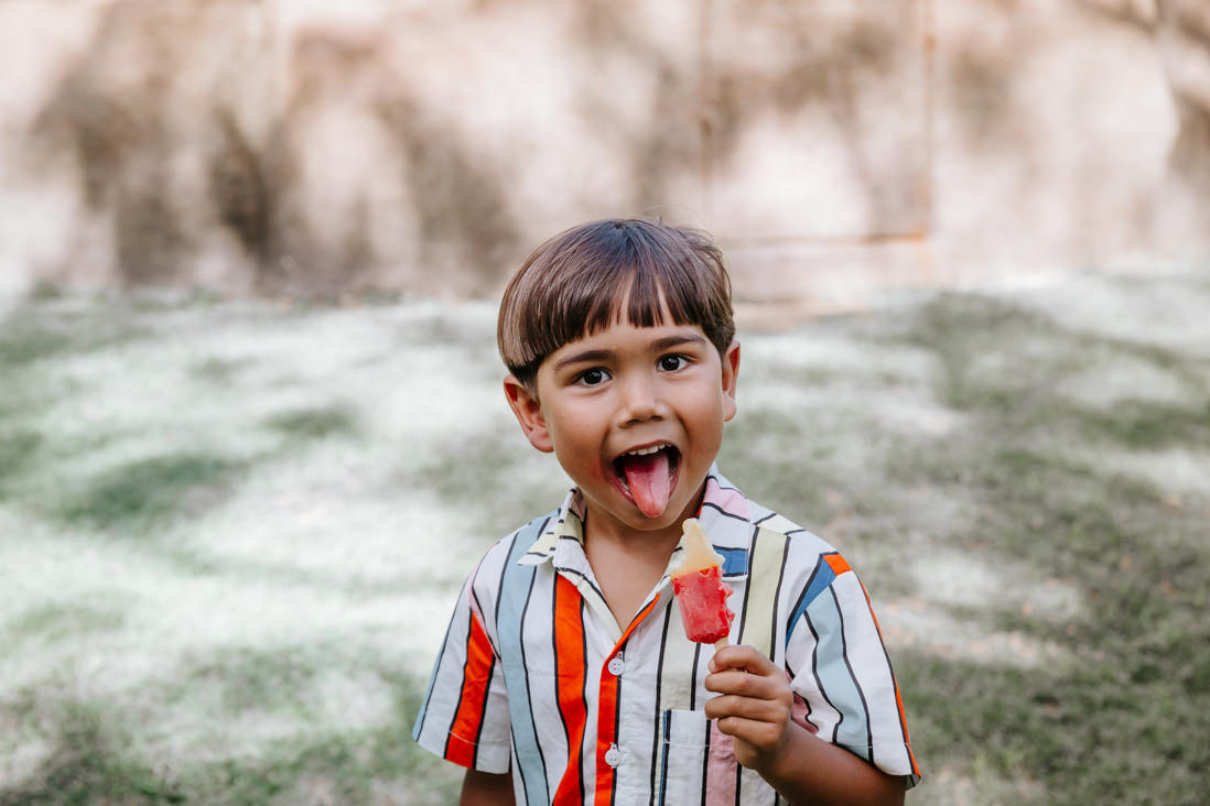 menino de 4 anos com picolé na mão da careta para foto