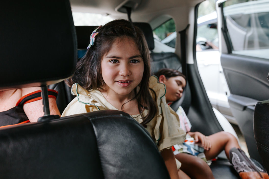 irmãos dentro do carro, a menina maior acordada o menino menor dorme