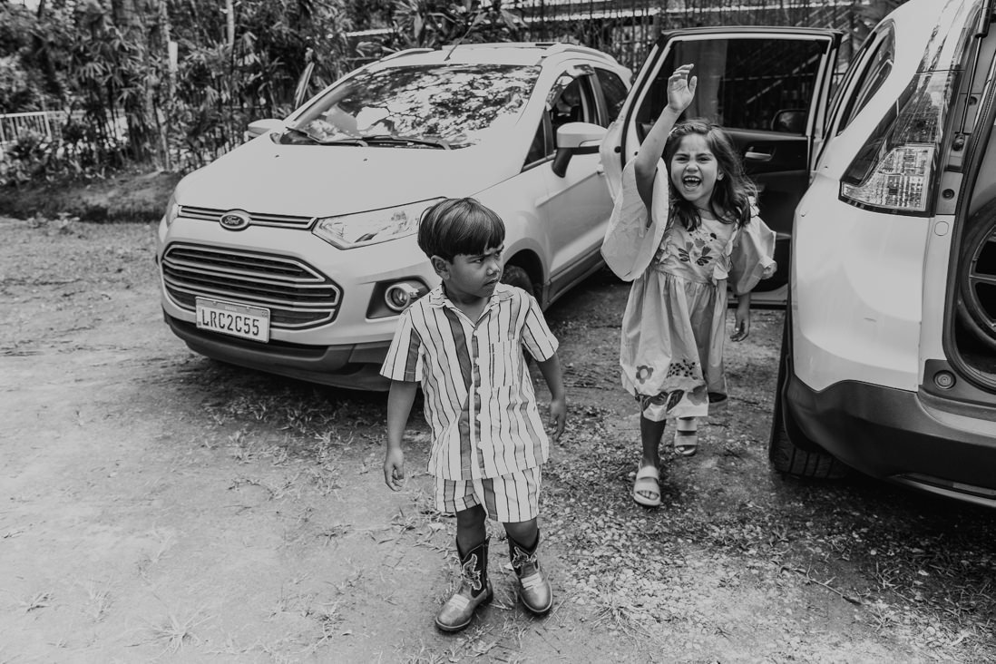 foto em preto e branco dos irmão descendo do carro e chegando na festa infantil no espaço jamboo em vargem grande rio de janeiro
