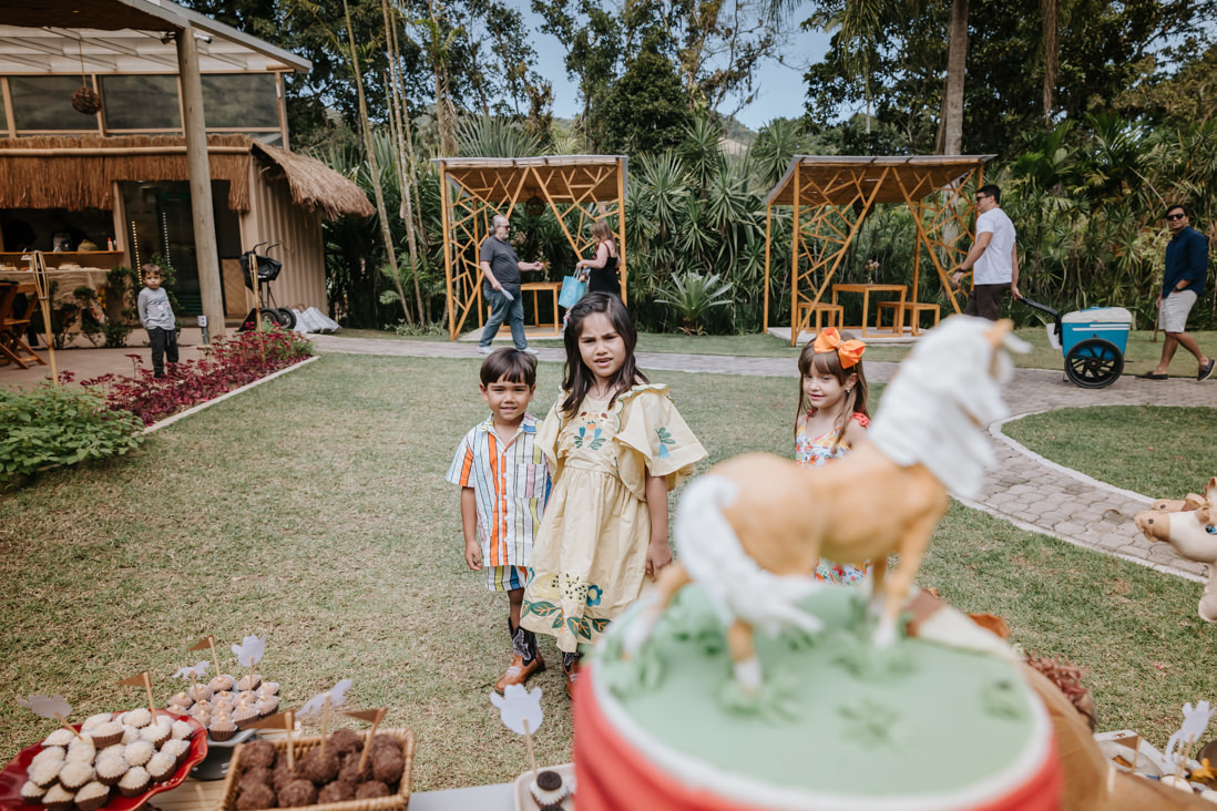 irmaos olham mesa de bolo com decoração afetiva no tema cowboy