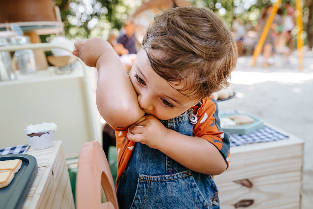 criança de 3 anos lambendo cotovelo sujo de chantilly
