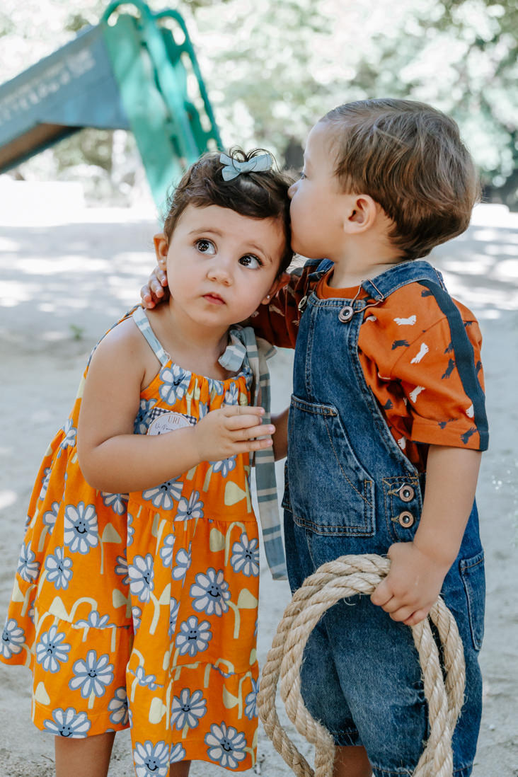 menino de 2 anos beija a cabeça de menina de 2 anos de vestido florido