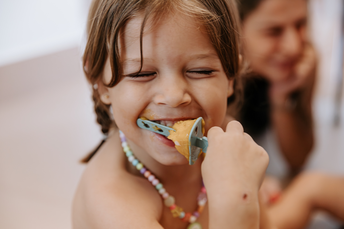 foto de close de uma menina de 5 anos tomando um picole de frutas