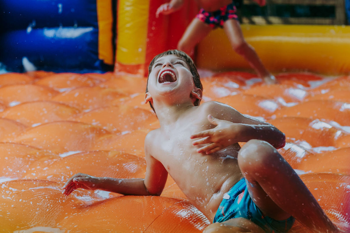 Fotografia de menino gargalhando no futebol de sabão em festa infantil em play de condomínio na Lagoa Rodrigo de Freitas no Rio de Janeiro