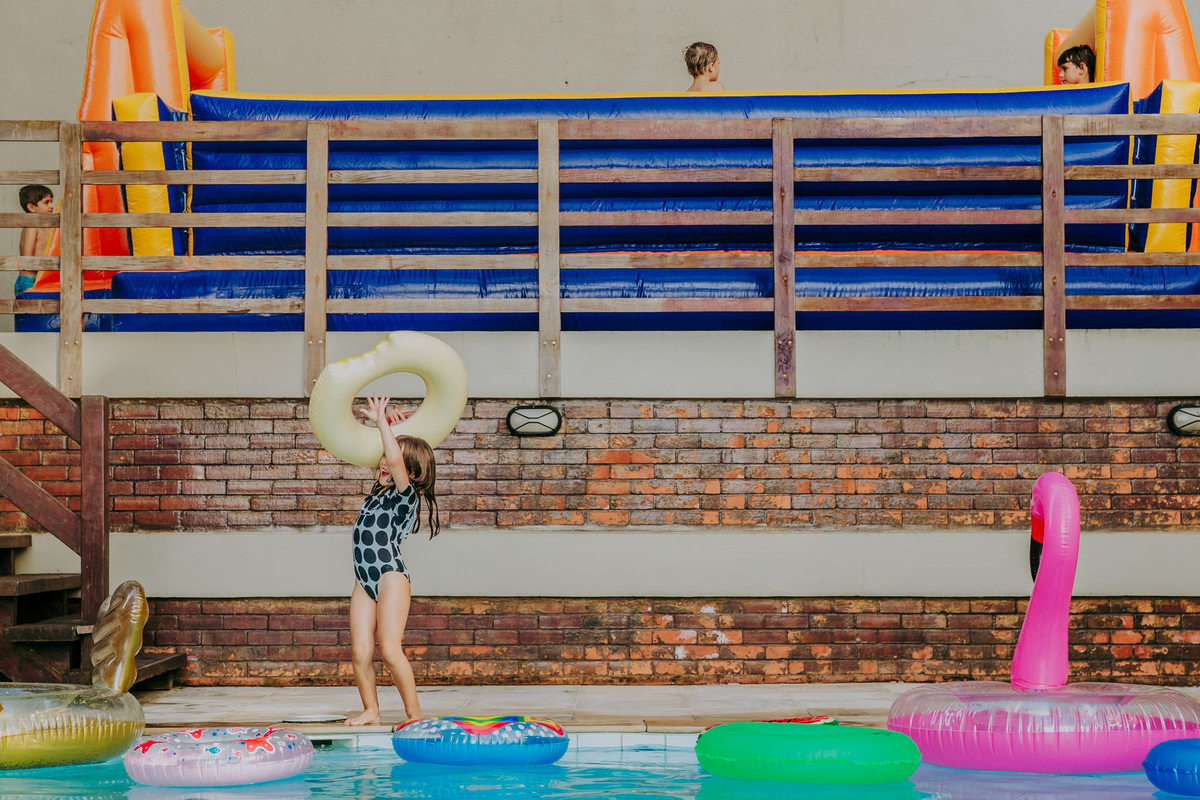 Fotografia de criança equilibrando boia na piscina em festa infantil no play do condomínio na Lagoa Rodrigo de Freitas no Rio de Janeiro