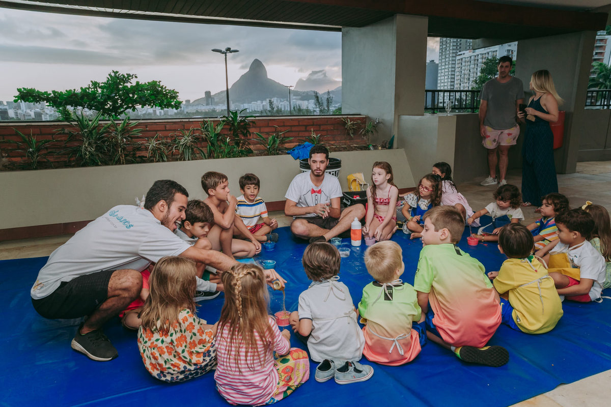 fotografia de criancas sentadinhas participando de recreação infantil com os recreadores da Fabulosos durante festa de irmãos no play de condomínio na Lagoa Rodrigo de Freitas no Rio de Janeiro